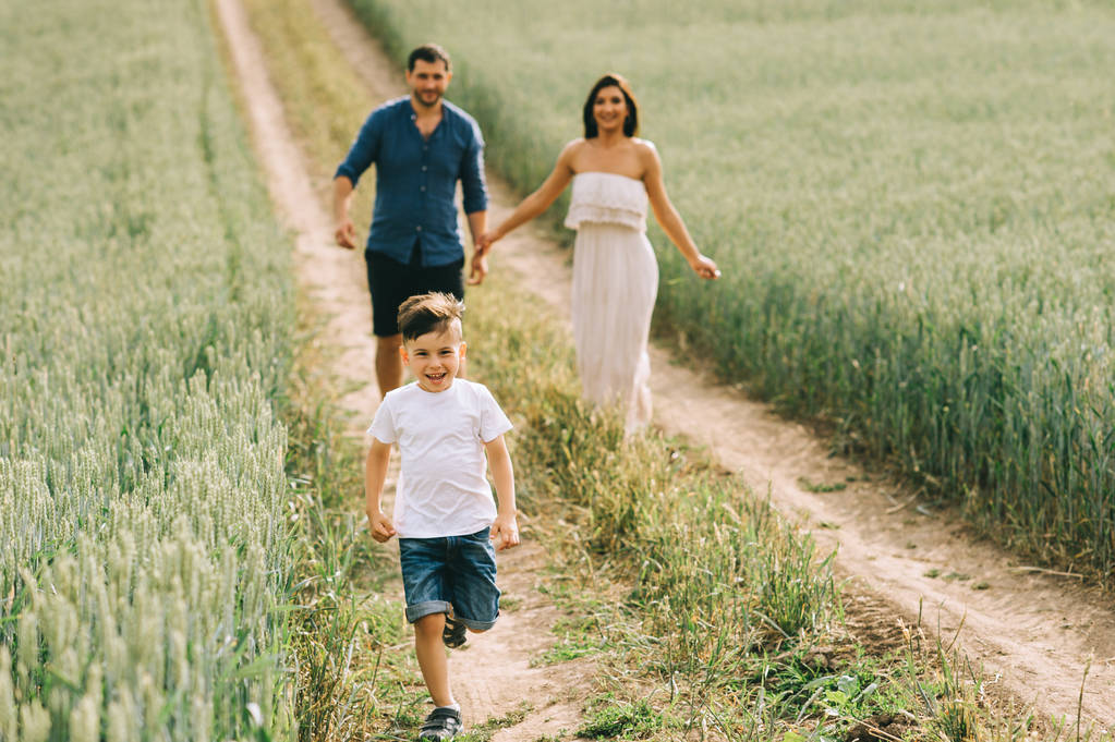 happy parents and son running on path in field - Photo, Image