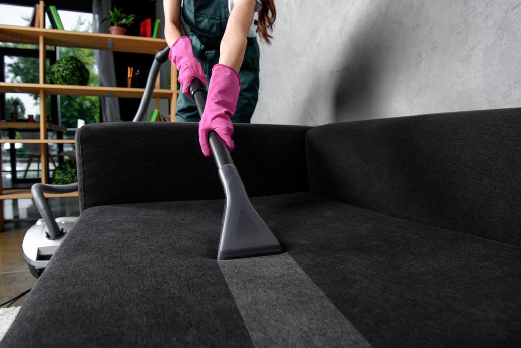 partial view of woman in rubber gloves cleaning furniture with vacuum cleaner   - Photo, Image