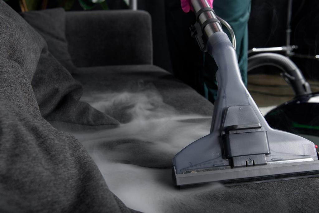 close-up view of person cleaning sofa with vacuum cleaner, hot steam cleaning concept - Photo, Image