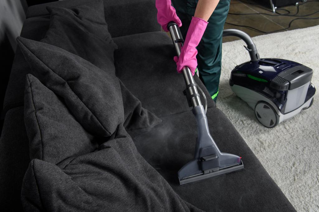 bijgesneden schot van persoon schoonmaken sofa met stofzuiger, bekleding reinigen concept - Foto, afbeelding