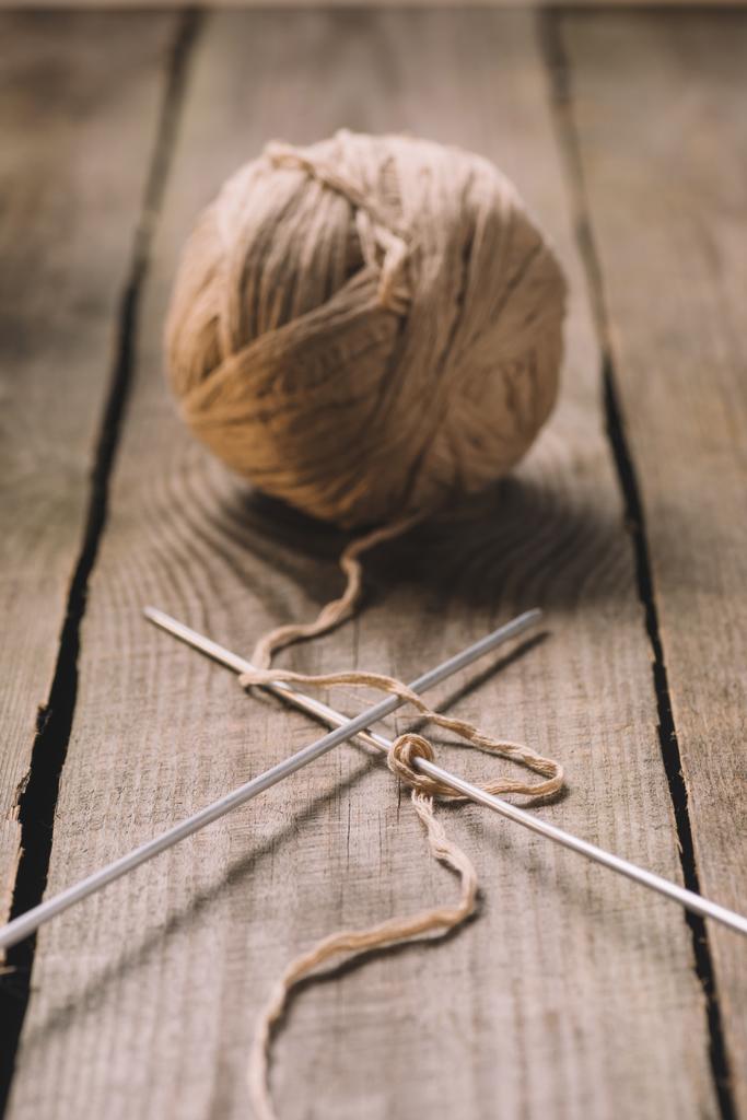 selective focus of beige knitted woolen yarn ball and knitted needles on wooden background  - Photo, Image