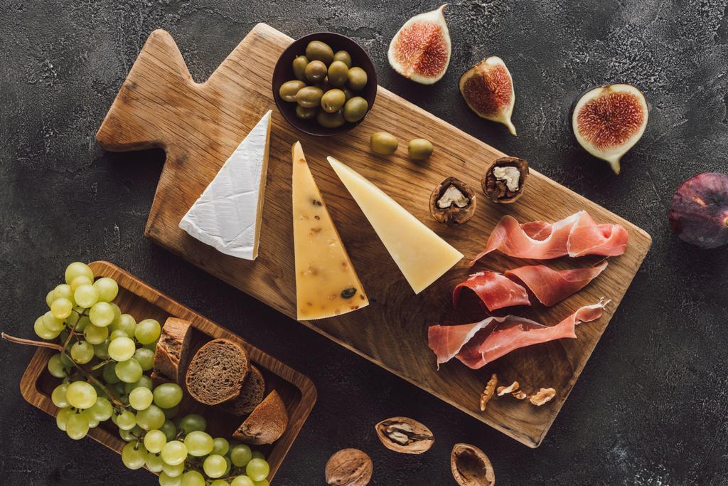 vista superior de queijo variado e frutas na mesa escura
 - Foto, Imagem