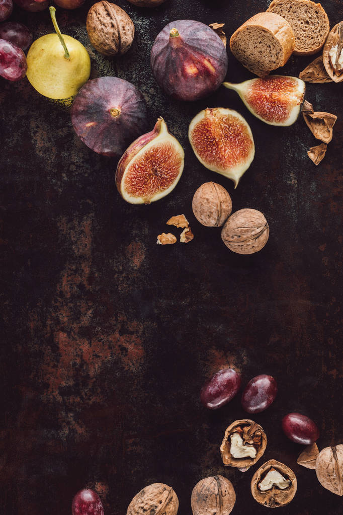 elintarvikkeiden koostumus valikoituja leipää, hedelmiä ja hasselpähkinöitä tummalla pinnalla
 - Valokuva, kuva