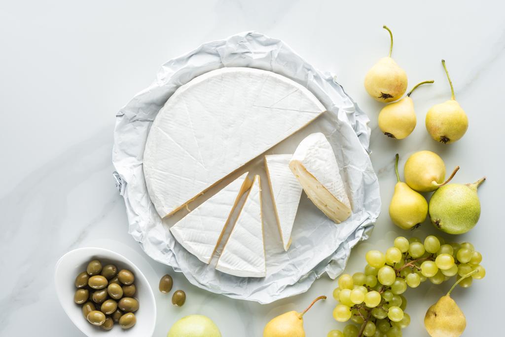 düz lay camembert peyniri, zeytin ve meyve beyaz mermer yüzeyi ile - Fotoğraf, Görsel