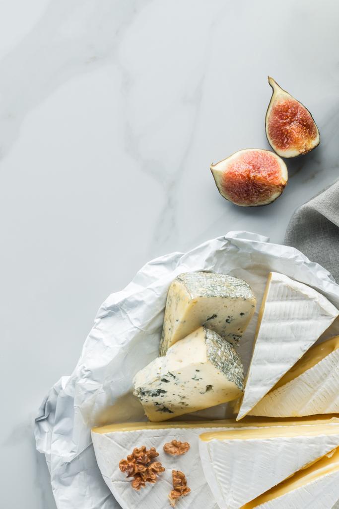 flat lay with assorted cheese and fig pieces on white marble surface - Photo, Image
