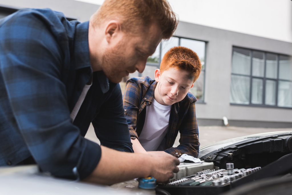 father and son repairing car with open hood and looking at broken part - Photo, Image
