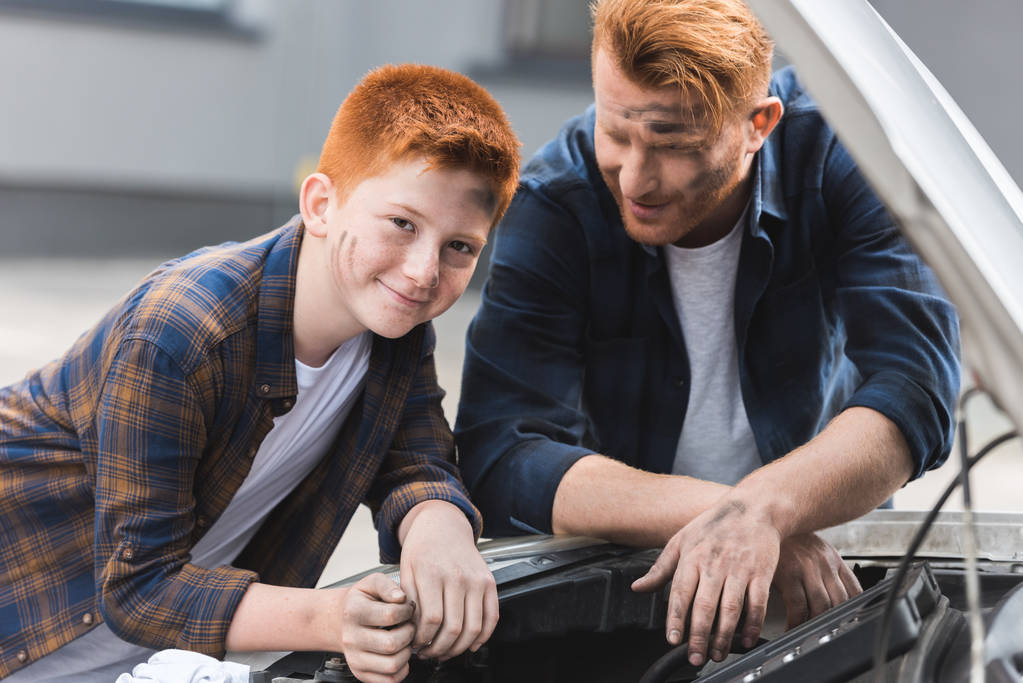 生姜髪父と息子オープン フード付きの車を修理 - 写真・画像