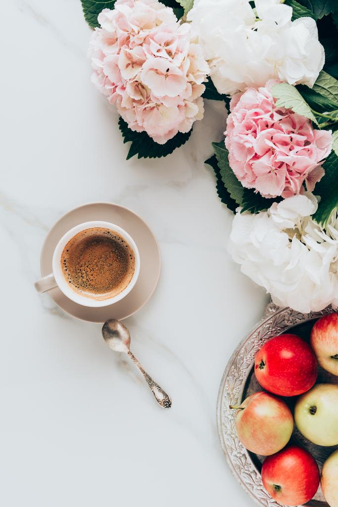 posa piatta con tazza di caffè, cucchiaio, mele e fiori di ortensia rosa sulla superficie di marmo
 - Foto, immagini