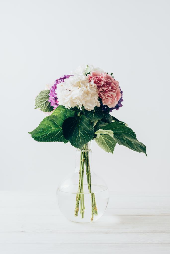πανέμορφη Ορτανσία πολύχρωμα λουλούδια σε γυάλινο βάζο, σε λευκό - Φωτογραφία, εικόνα