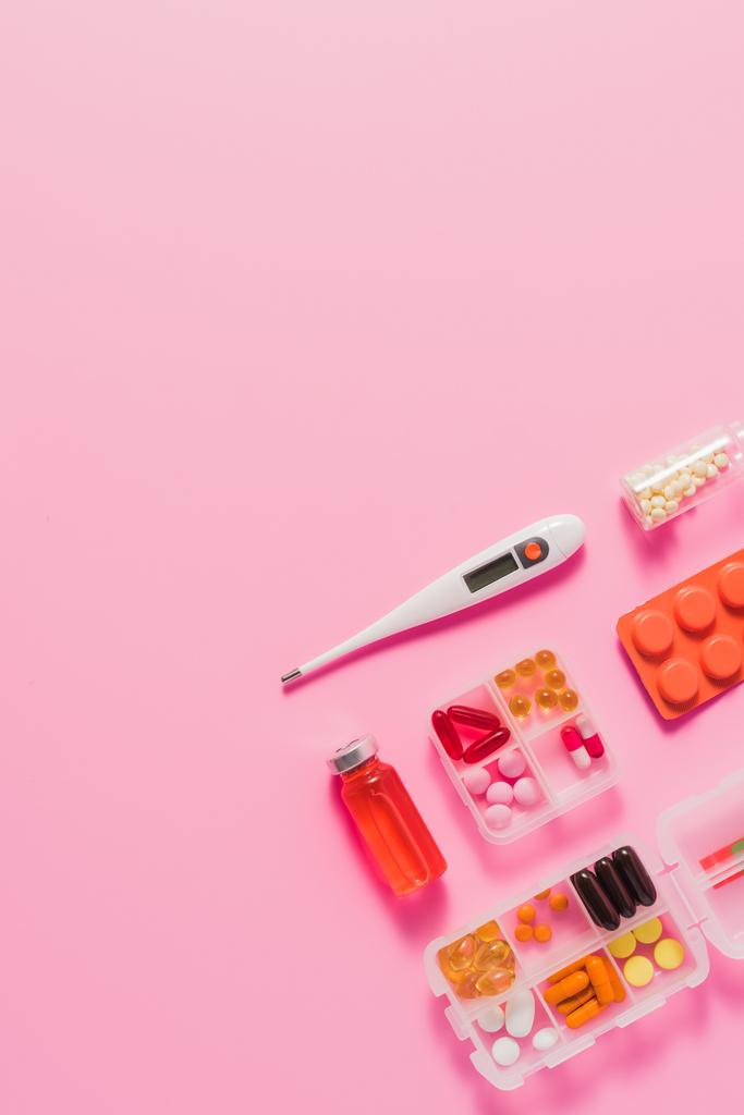 vista superior de diferentes medicamentos y termómetro eléctrico en rosa
 - Foto, imagen