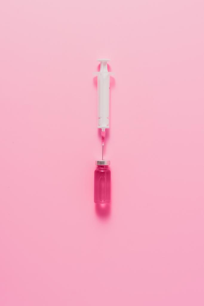 vista superior de la jeringa con ampolla de líquido rosa sobre la superficie rosa
 - Foto, imagen
