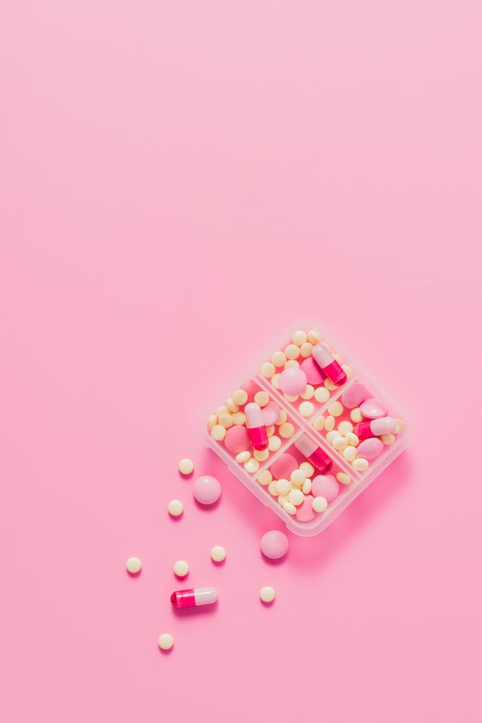 vista superior del recipiente de plástico con varias píldoras en rosa
 - Foto, imagen
