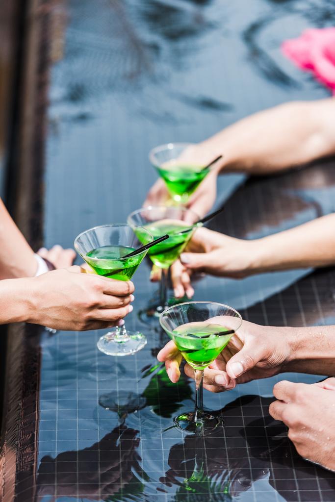 обрезанный образ друзей звон стаканов с коктейлями возле бассейна
  - Фото, изображение