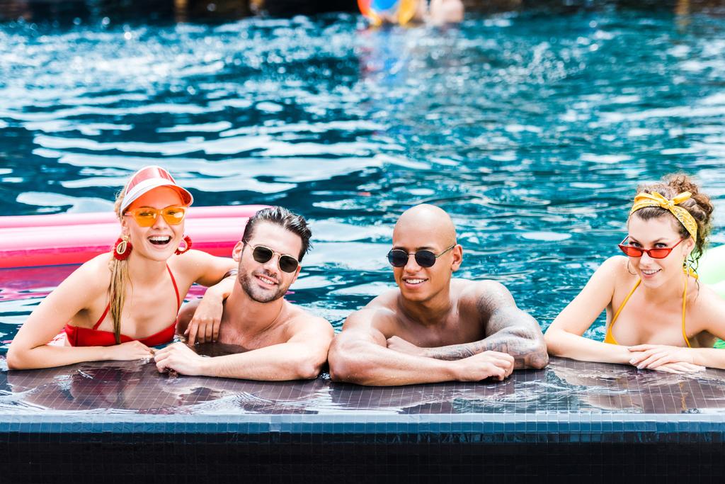 amigos sorridentes em óculos de sol descansando na piscina
  - Foto, Imagem
