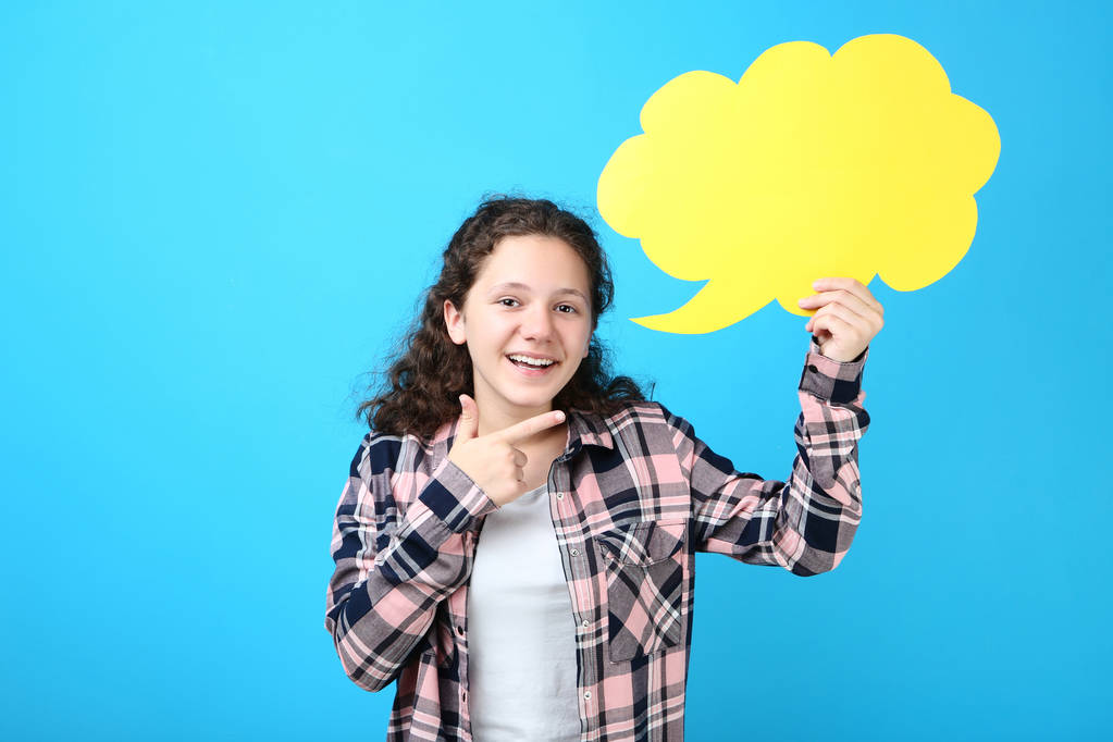 Menina segurando bolha de fala e apontando o dedo de lado no fundo azul
 - Foto, Imagem