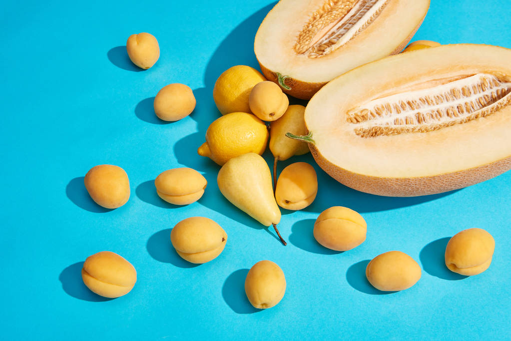 высокий угол обзора вкусных спелых груш, абрикосов, дыни и лимонов на голубой
  - Фото, изображение