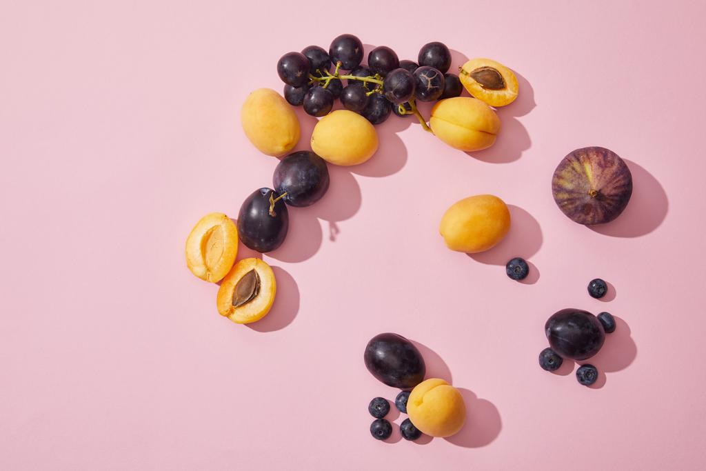 top view of fresh ripe sweet apricots, grapes, plums, blueberries and fig on purple background - Photo, Image