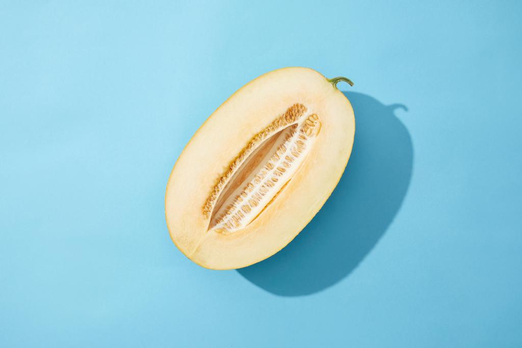 pohled shora na polovinu čerstvé zralého sladkého melounu na modrém pozadí - Fotografie, Obrázek