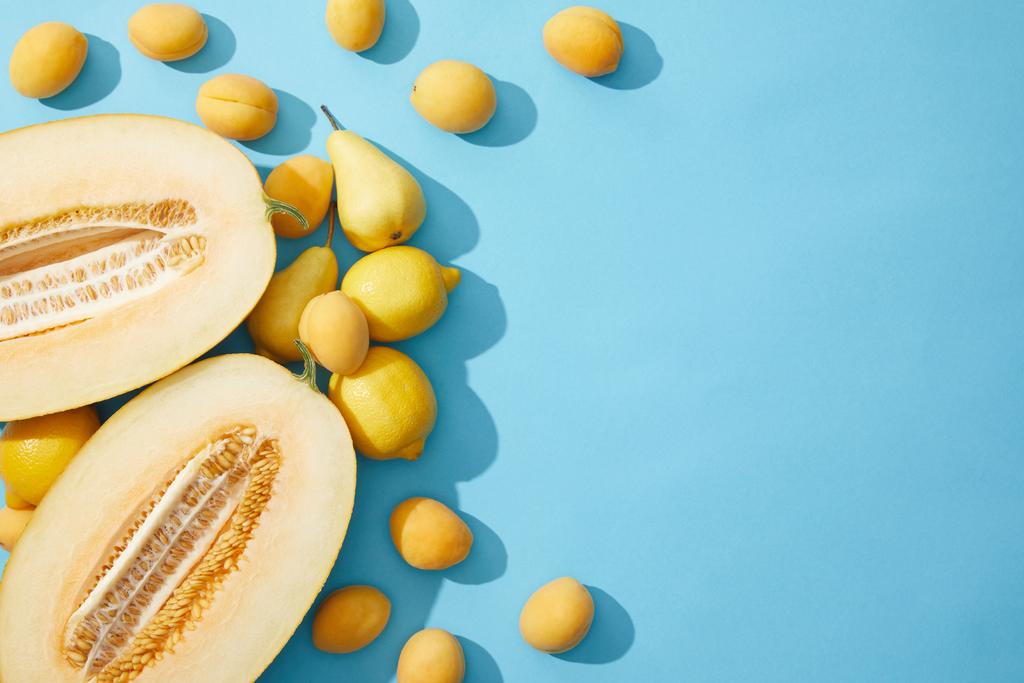青の背景に新鮮な熟したメロン、梨、レモン、アプリコットのトップ ビュー - 写真・画像