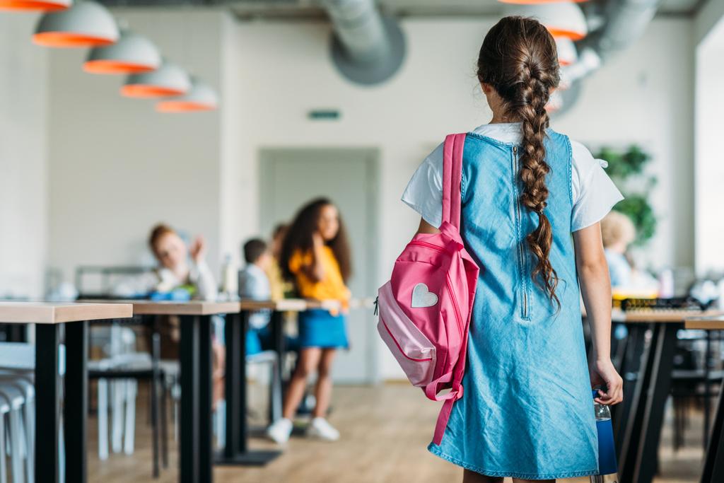 Achteraanzicht van weinig schoolmeisje in jurk wandelen op Schoolcafetaria - Foto, afbeelding