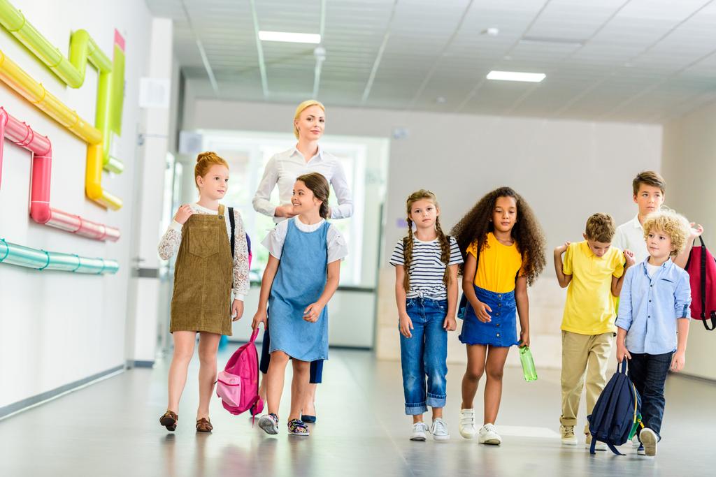 група щасливих багатоетнічних однокласників, що ходять по шкільному коридору
 - Фото, зображення