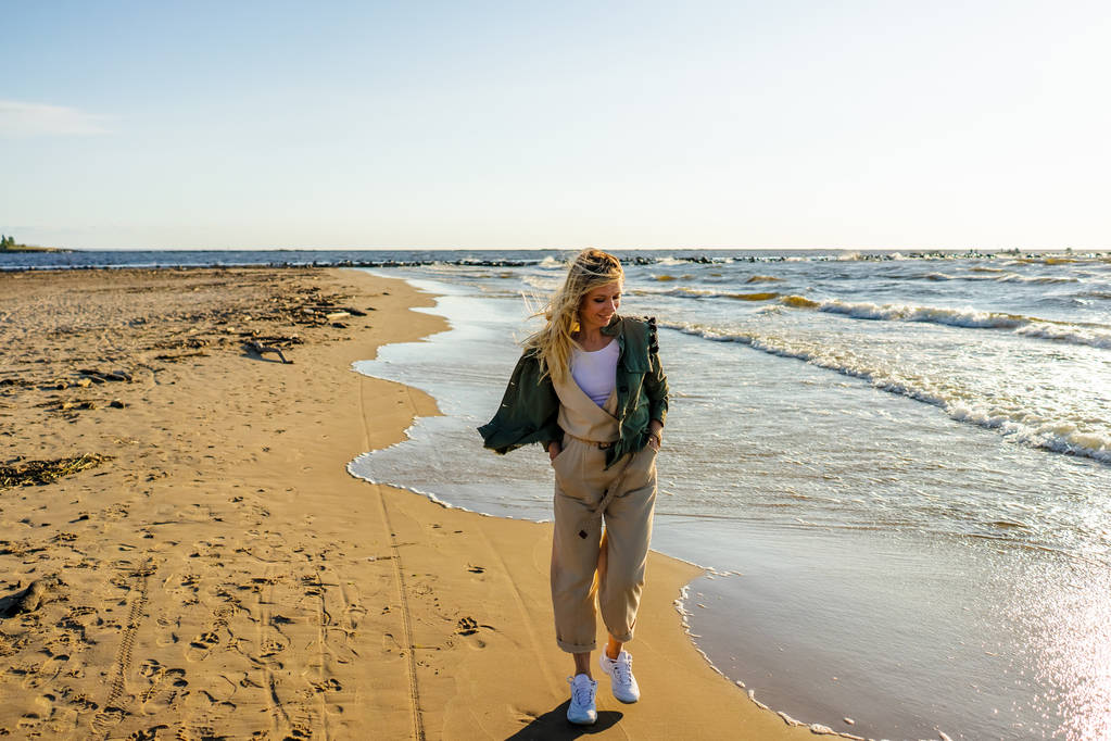 junge lächelnde Frau in stylischer Kleidung am Strand an einem Sommertag - Foto, Bild