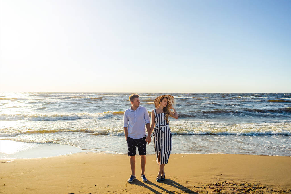 Młoda para w miłości, trzymając się za ręce na piaszczystej plaży w Rydze, Łotwa - Zdjęcie, obraz