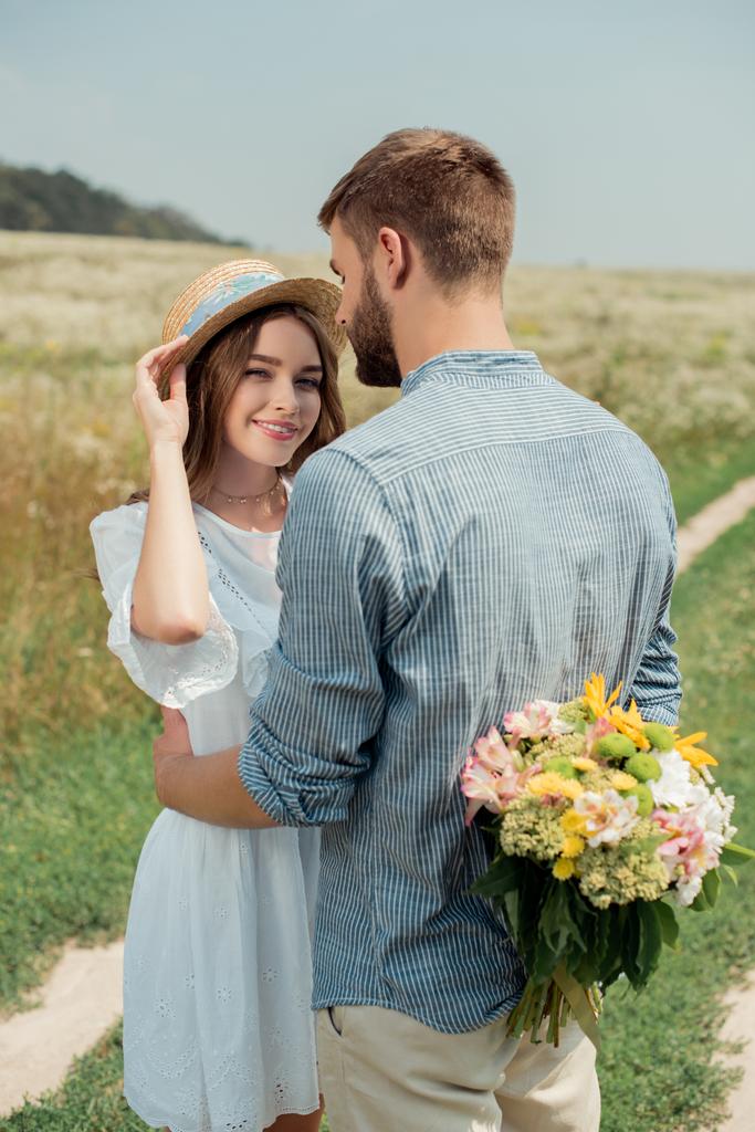 uomo nascondendo bouquet di fiori selvatici per la ragazza dietro la schiena nel campo estivo
 - Foto, immagini