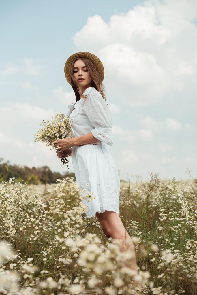 çayır üzerinde yabani papatya çiçekler Buket beyaz elbiseli güzel kadın - Fotoğraf, Görsel