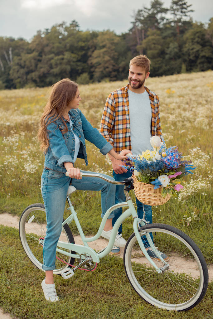 усміхнені молоді коханці з ретро велосипедом на полі з дикими квітами
 - Фото, зображення