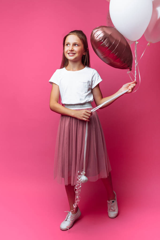 Porträt eines Mädchens mit Luftballons im Atelier, auf rosa Hintergrund - Foto, Bild