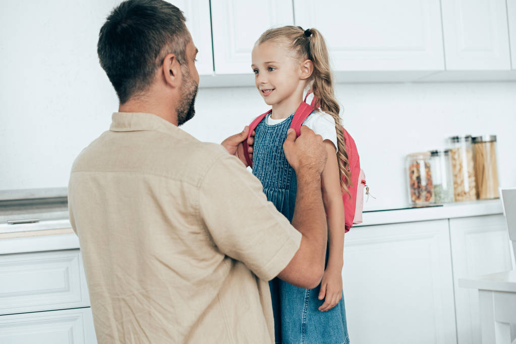 portrait of smiling father and little daughter with backpack at home, back to school concept - Photo, Image