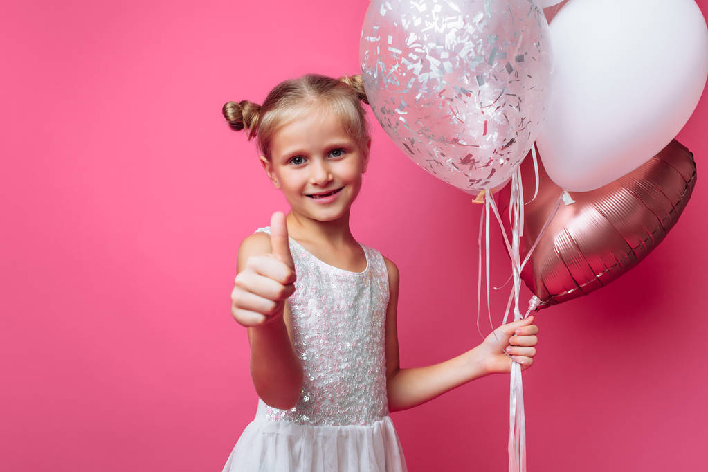 Porträt eines kleinen Mädchens mit Kugeln auf rosa Hintergrund in einem Fotostudio - Foto, Bild