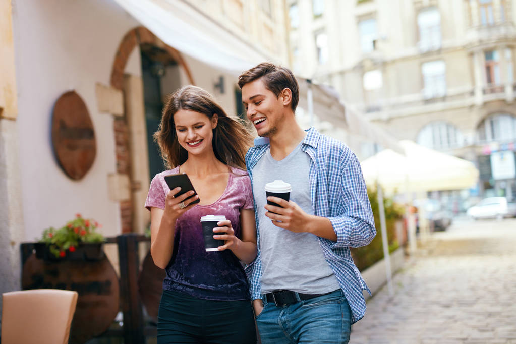 Couple utilisant le téléphone portable et boire du café en plein air
 - Photo, image