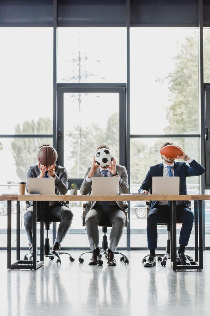 giovani uomini d'affari che tengono le palle mentre lavorano con i computer portatili in ufficio
   - Foto, immagini