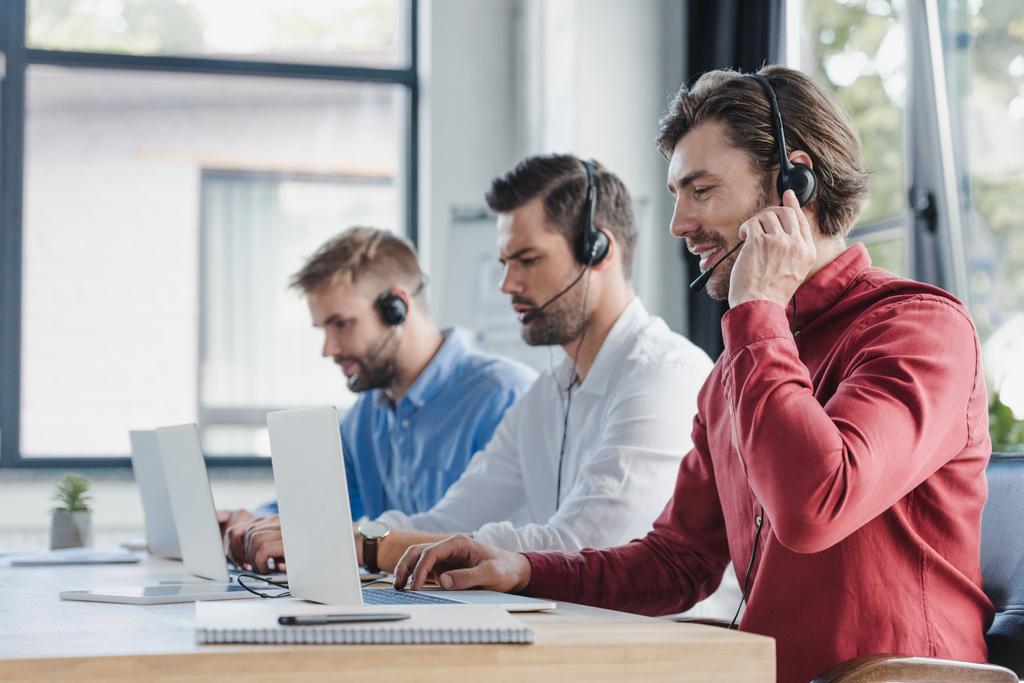 üç genç dizüstü bilgisayarlar kullanma office kulaklık merkezi operatörleri çağırın - Fotoğraf, Görsel