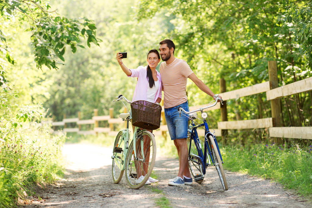 couple with bicycles taking selfie by smartphone - Photo, Image