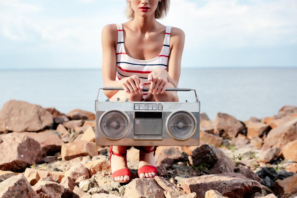 vista recortada de la niña posando con boombox vintage en la orilla rocosa
 - Foto, imagen