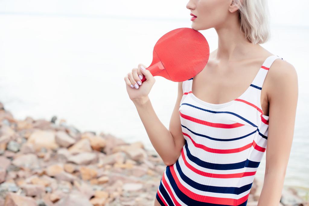 vista recortada de la mujer en traje de baño de rayas retro posando con raqueta de tenis de mesa
  - Foto, Imagen