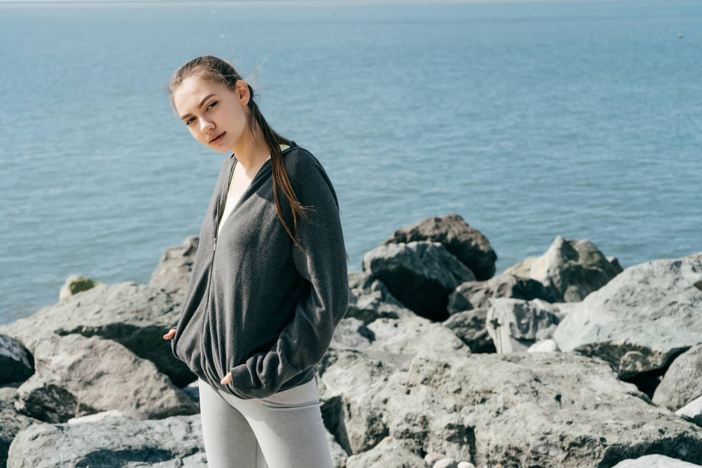 confident young girl in sportswear resting after jogging by the sea - Photo, Image