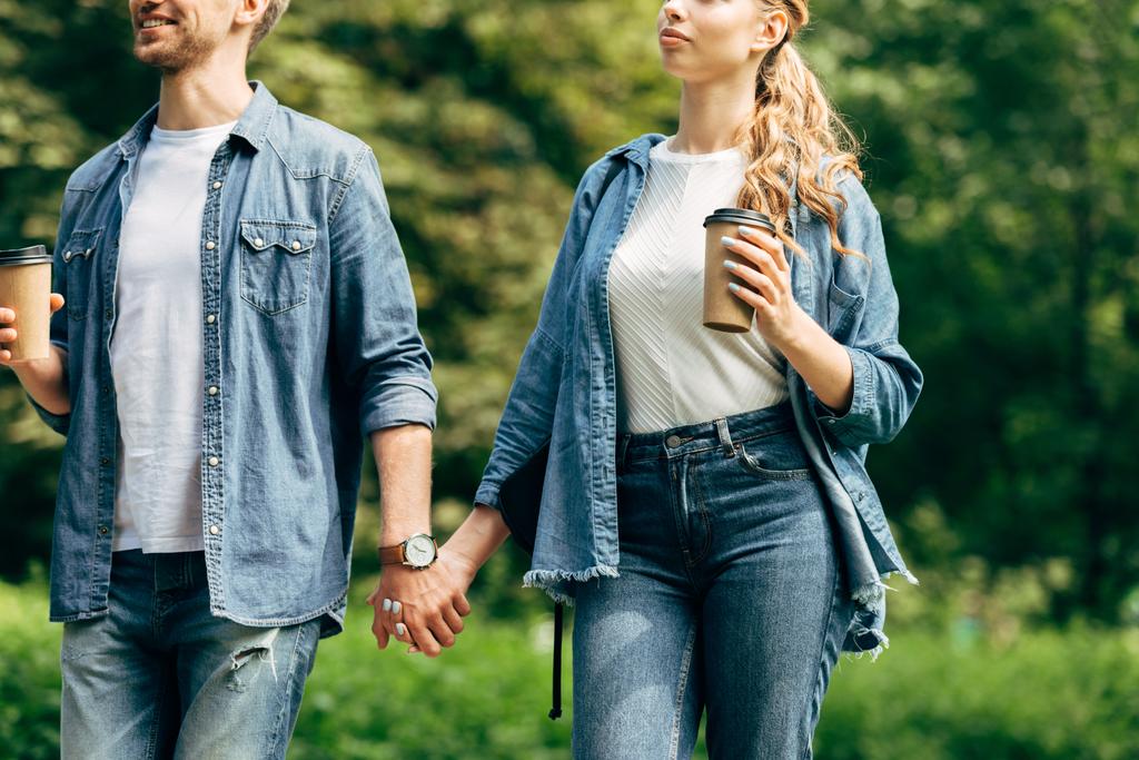 rajattu kuva nuoresta parista paperikuppien kanssa kävelemässä puistossa yhdessä
 - Valokuva, kuva