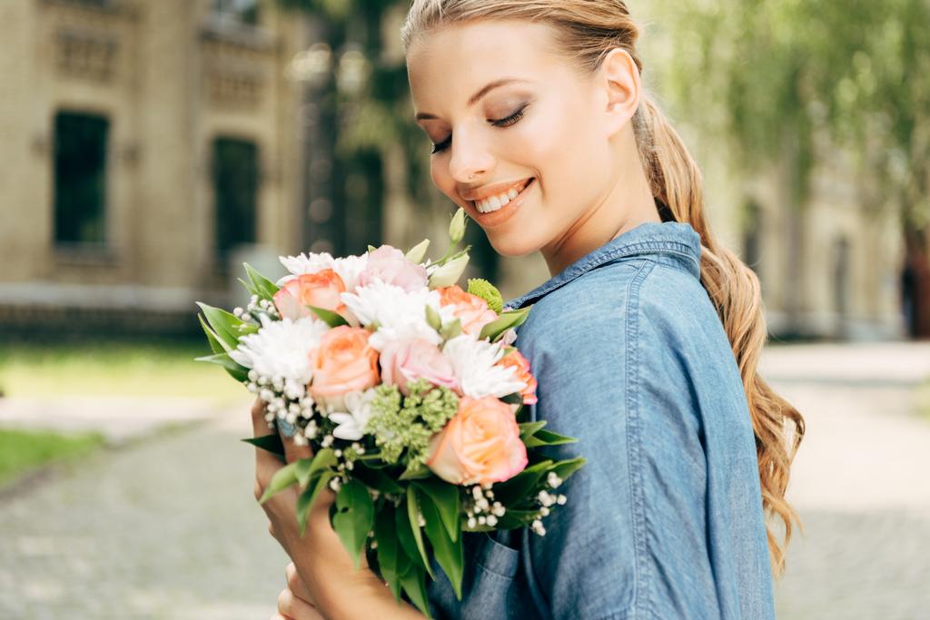 souriant jeune femme regardant bouquet de fleurs
 - Photo, image