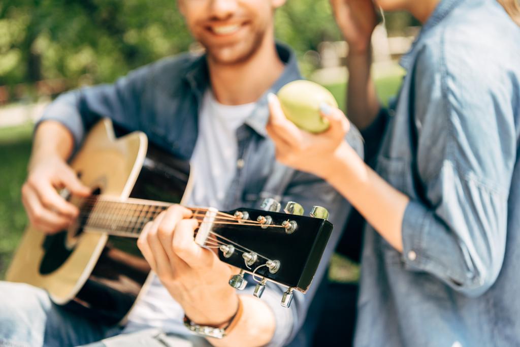 περικοπεί shot του ανθρώπου παίζει κιθάρα για φίλη στο πάρκο - Φωτογραφία, εικόνα