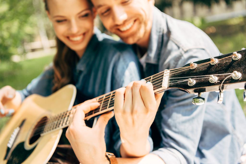 plan rapproché de jeune femme heureuse avec petit ami jouant de la guitare ensemble au parc
 - Photo, image