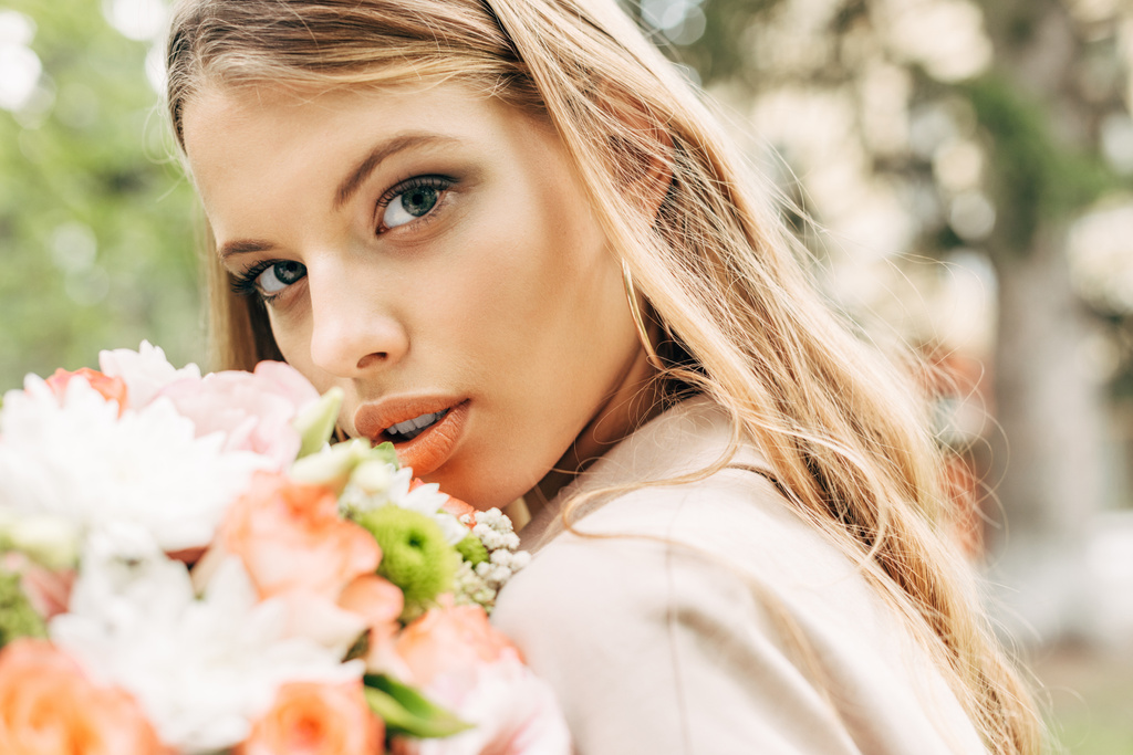gyönyörű fiatal nő, virág csokor látszó-on fényképezőgép makró portréja - Fotó, kép