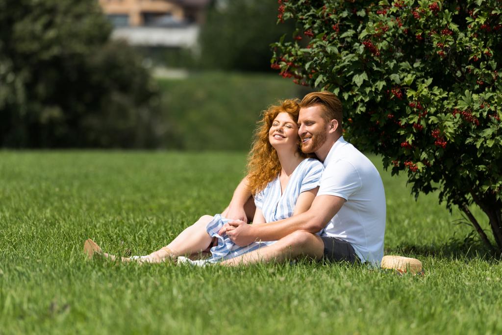sorrindo casal ruiva sentado e se divertindo na grama no parque
 - Foto, Imagem