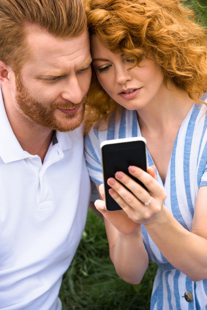 rousse femme montrant smartphone à copain en plein air
  - Photo, image