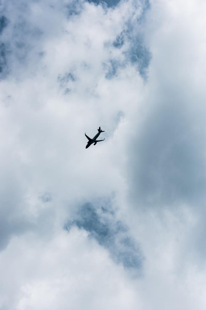 青い曇り空を飛んでいる飛行機の低角度のビュー ロイヤリティフリー写真 画像素材