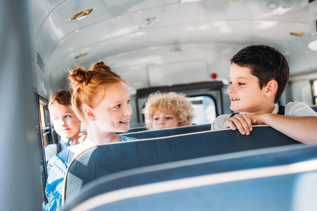 ryhmä iloisia pieniä oppilaita koulubussissa
 - Valokuva, kuva