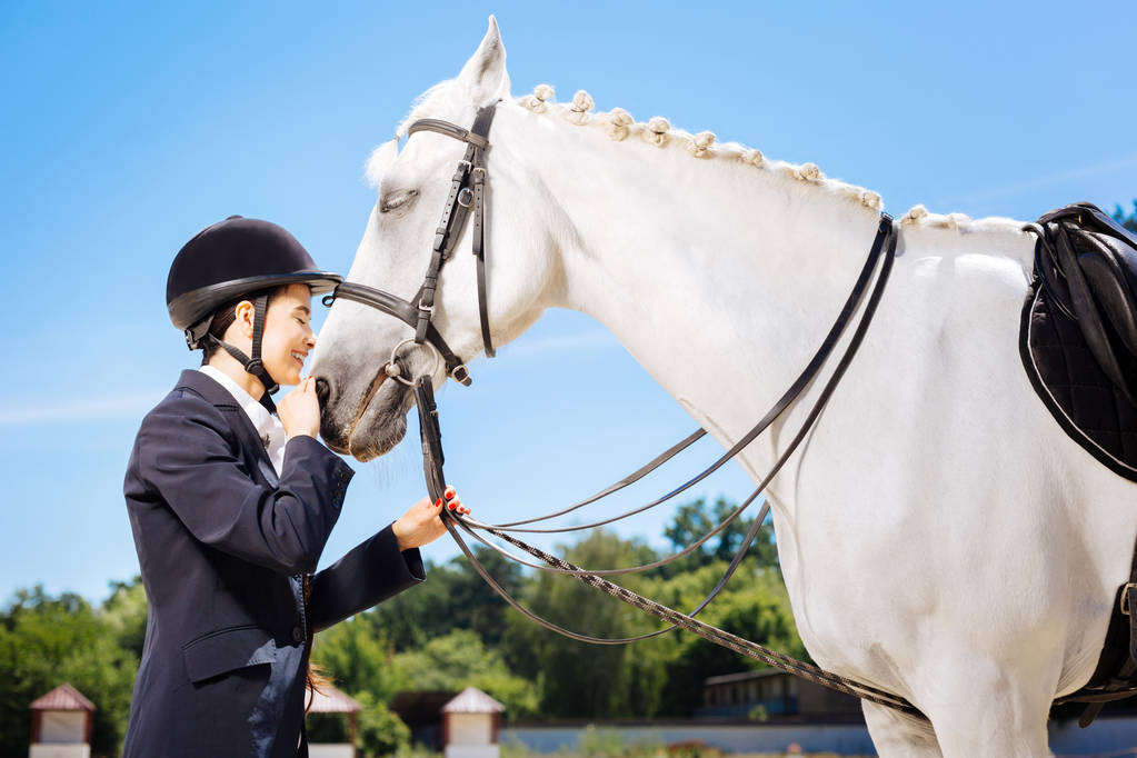 Vrouwelijke rider haar witte paard zeer liefdevolle zorg - Foto, afbeelding
